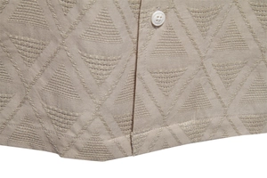 Macro shot of khaki shirt fabric with geometric triangle texture and white button detail