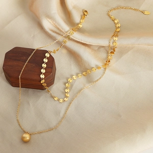 Double-layered 18K gold plated titanium necklace with ball pendant on silk backdrop