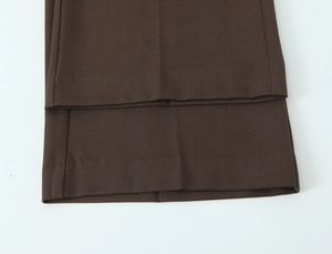 Macro shot of dark brown trousers hem showcasing twill fabric texture and drape