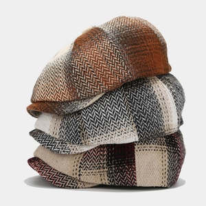 Close-up of three autumn wool newsboy caps featuring vintage herringbone and plaid patterns