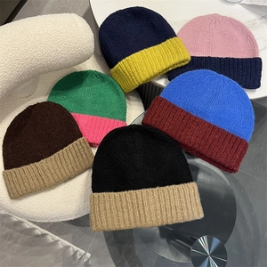 Collection of colorful two-tone knit beanies displayed on soft textured background