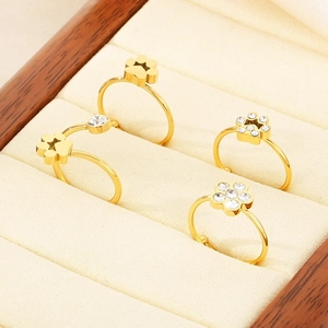 Set of four gold-plated rings with clover and flower designs in a wooden jewelry box