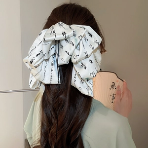 Detail of oversized white satin bow hair clip with black Chinese calligraphy on long hair