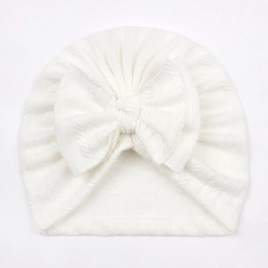 White ribbed knit baby turban hat featuring a large decorative bow for infants