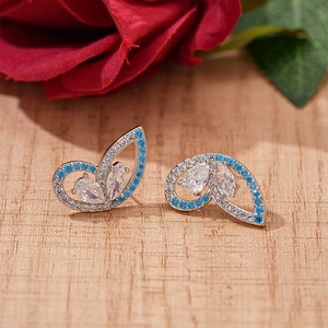 Exquisite butterfly earrings with sky blue and white zircon on a natural wood surface