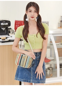 Detailed shot of rainbow straw crossbody bag with white leather strap in cafe setting