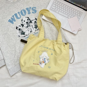 Close-up of a pale yellow canvas drawstring bag featuring a cute cartoon dog embroidery
