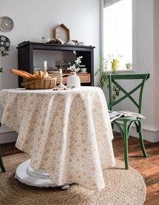 Close-up of festive cream linen tablecloth with gold reindeer and snowflake patterns