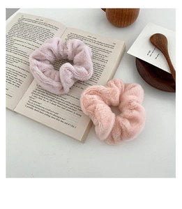 Close-up of soft pink faux rabbit fur scrunchies placed on an open vintage book