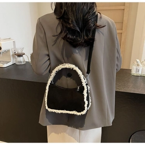 Detail of contrast lamb wool trim and black fabric on the shoulder bag with silver zipper