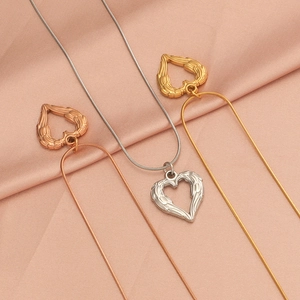 Detailed view of heart with wings necklaces in gold, rose gold, and silver on pink silk
