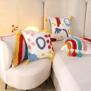 Set of four tufted rainbow throw pillow covers with tassels on a white sofa