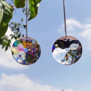 Set of 2 K9 crystal suncatchers with rainbow prisms hanging against a blue sky background
