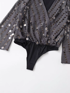 Detail of grey V-neck bodysuit featuring vertical sequins and long sleeves on white background
