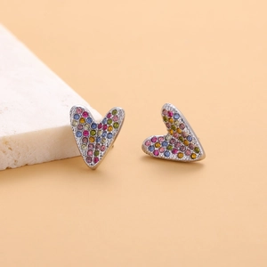 Detailed view of silver heart earrings with colorful zircon inlay on a stone prop