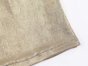 Macro view of gold metallic fabric texture and fine stitching detail on halter top