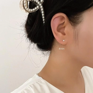 Detail of 4mm zircon stud earrings and a minimalist pearl hair clip worn by a model