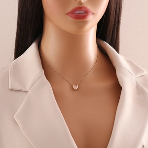 Pink heart pendant necklace in gold finish worn by model over a beige blazer