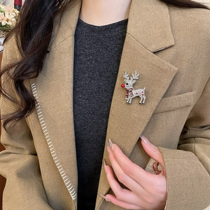 Macro detail of Christmas reindeer brooch with clear rhinestones on khaki suit jacket