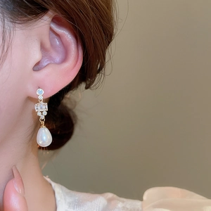 Close-up of teardrop pearl earring with zircon inlays and 18k gold plating on a model