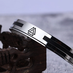 Macro shot of silver Valknut viking runes engraved on a stainless steel cuff bracelet