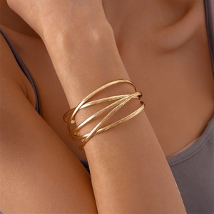 Close-up of golden multi-layer geometric cuff bracelet with brushed metallic texture