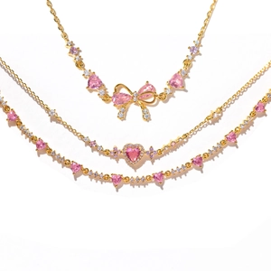 Detailed view of three gold bracelets featuring pink heart-shaped stones and bow designs