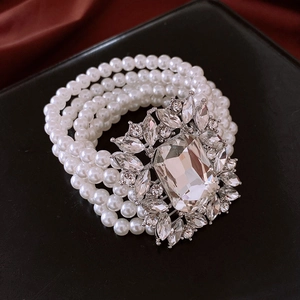 Detail of multi-strand pearl bracelet featuring a large sparkling crystal centerpiece