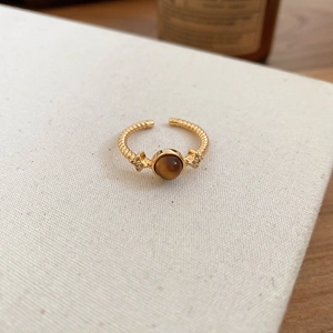 Detail of twisted gold ring featuring a brown tiger eye stone and small crystals