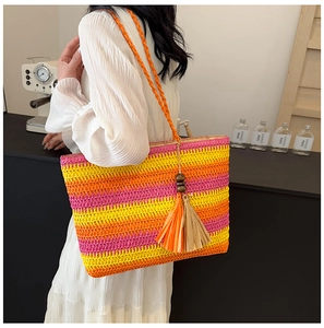 Detail of colorful woven straw tote bag with rainbow stripes and fringe tassel accessory