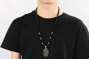 Detail of beaded necklace for men featuring a gold lion head pendant on black beads