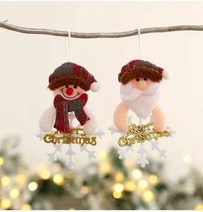 Detail of plush snowman and Santa ornaments hanging on tree with gold Merry Christmas sign