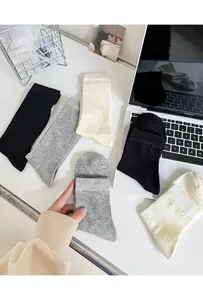 Detailed rib-knit texture of combed cotton crew socks in black, grey, and off-white colors