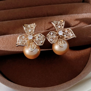 Vue détaillée de boucles d'oreilles fleur en zircon avec perles dorées dans un écrin