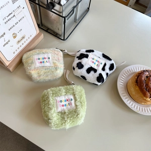 Detailed close-up of mini plush makeup bags in cow print, knit, and green faux fur
