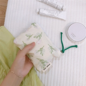 Close-up of small floral cotton pouch with green leaf patterns and zipper detail