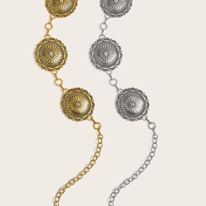 Detail of vintage bohemian concho waist chains in gold and silver with embossed metal texture