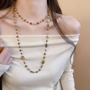 Detail of layered gold beaded necklace with brown Maillard style beads on model