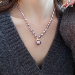 Détail d'un collier de perles mauves avec un pendentif doré orné de petits diamants