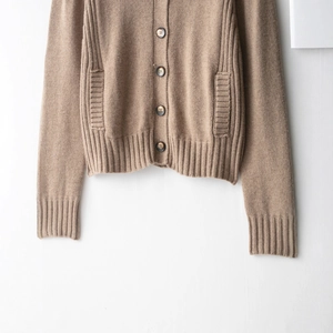 Brown knit cardigan sweater featuring dark round buttons and ribbed cuffs on white backdrop