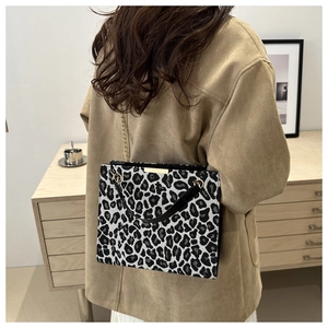 Detail of leopard print shoulder bag with gold chain strap on a camel wool coat model