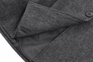 Makro-Detail des anthrazitfarbenen Tweed-Blazers mit hochwertigem schwarzem Knopf und Futter