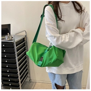 Side view of model wearing a bright green nylon crossbody bag with adjustable wide strap