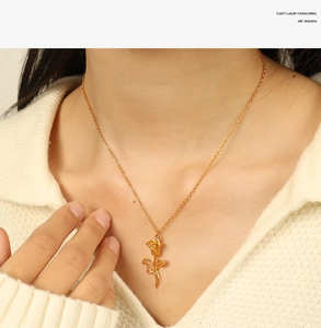 Detailed close-up of a 3D gold rose pendant necklace on a woman's collarbone