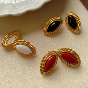 Macro view of vintage gold oval stud earrings with black, white and red stones