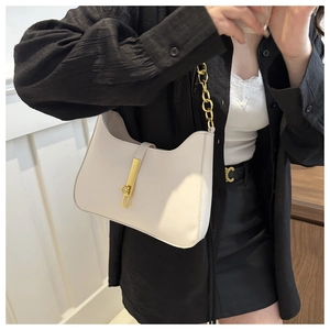 Detail of cream hobo bag with gold metal clasp and chain strap on a model