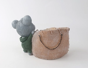 Dettaglio di fioriera in resina a forma di koala con maglione verde e sacco marrone