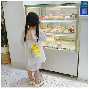 Girl wearing yellow bucket bag with bow and heart prints in a pastry shop scene