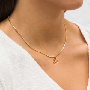 Gros plan d'un collier doré en acier inoxydable avec pendentif lettre W sur un mannequin