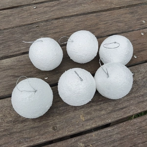 Set of 6 white foam Christmas balls with silver hanging strings on wooden floor